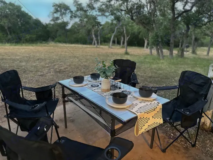 Enjoying an outdoor meal at our RV rental campsite. Portable table and chairs are set for a relaxing dinner amidst nature.. Sunset Park RV SunRay 2023