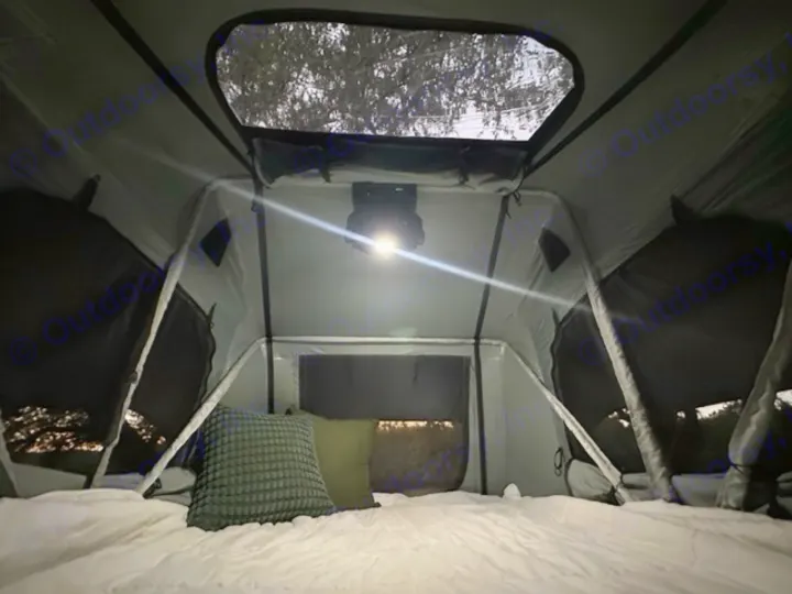 Cozy RV rental tent interior with bed, pillows, and bright overhead light for a comfortable night.. Sunset Park RV SunRay 2023