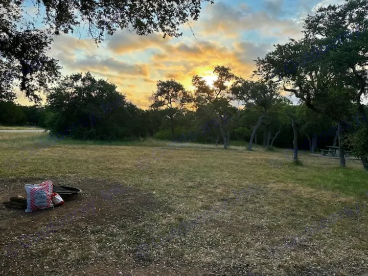 RV rental camping: serene campsite at sunset with a fire pit & picnic table in a natural setting.. Sunset Park RV SunRay 2023