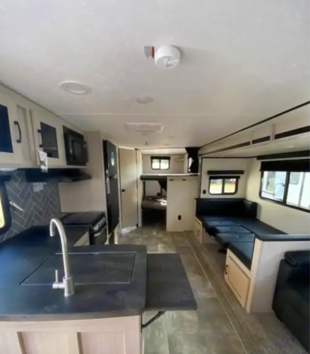 Tour this modern **rv rental** interior featuring a spacious kitchen island, comfortable lounge seating, and dedicated bunk beds.. Coachmen Other 2022