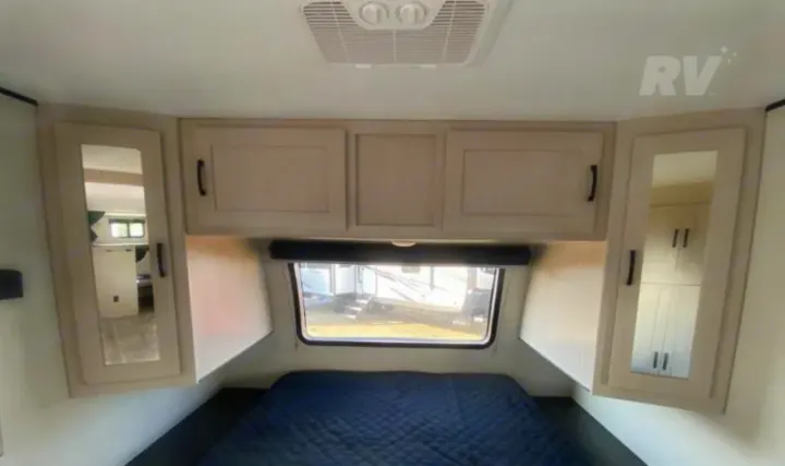 Cozy RV rental bedroom with a dark quilted bed, window, mirrored cabinets, and ceiling AC. Ideal for your next camper adventure.. Coachmen Other 2022