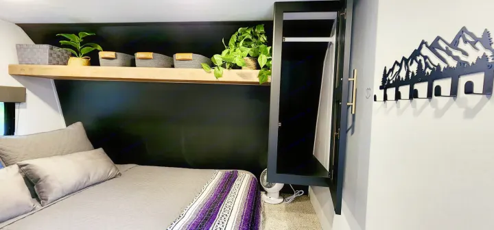 RV rental bedroom with sleek black wall, comfy bed, shelf decor, and mountain hooks.. Keystone RV Springdale 2022