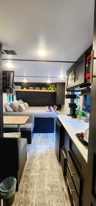 Modern RV rental interior. A sleek kitchen, dining area, and cozy bedroom are visible, featuring dark cabinets and light accents.. Keystone RV Springdale 2022