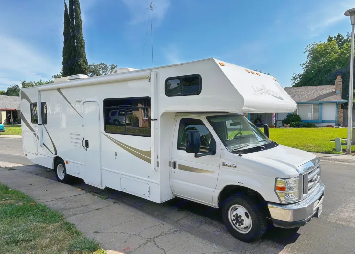 White Ford E-450 Majestic RV rental motorhome parked on a sunny residential street.. Thor Majestic 2015