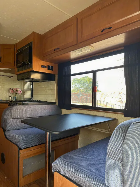 Inside this RV rental: functional kitchen with microwave, comfortable dinette seating, and large windows offering outdoor views.. Thor Majestic 2015