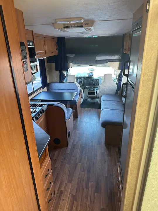 Inside an rv rental: cozy dining booth, kitchen appliances, and comfy overhead sleeping area.. Thor Majestic 2015