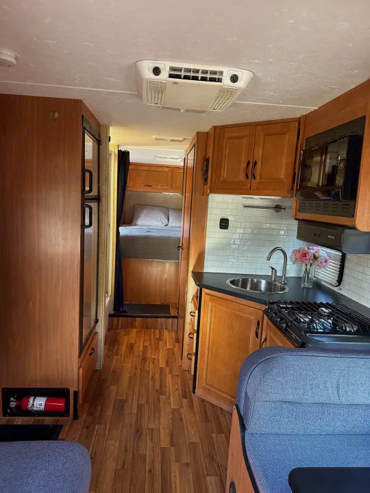 Explore this well-equipped RV rental interior! Features a compact kitchen, comfortable bed, and cozy living area.. Thor Majestic 2015