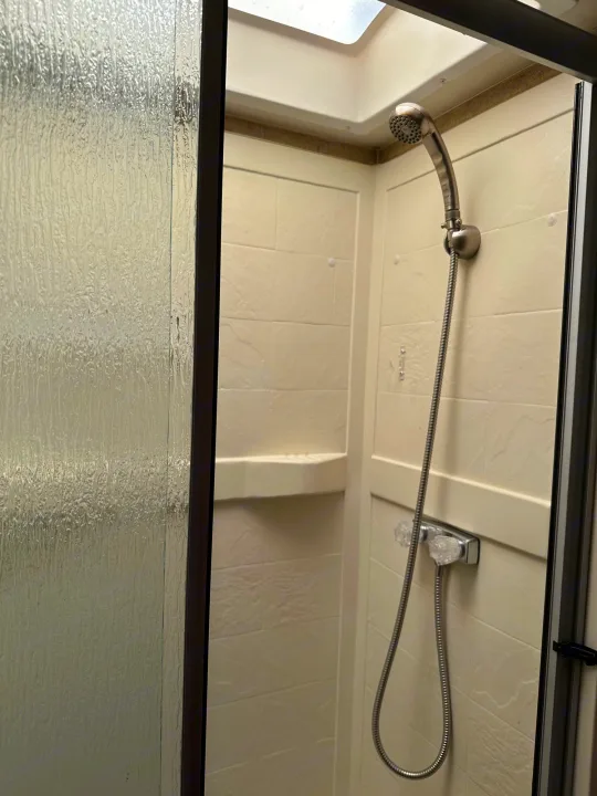 This RV rental features a compact shower with a handheld showerhead and frosted glass door.. Thor Majestic 2015