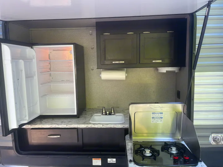 This RV rental features a convenient outdoor kitchen with a mini-fridge, sink, and two-burner stove, perfect for camping.. Jayco Jay Flight 2021