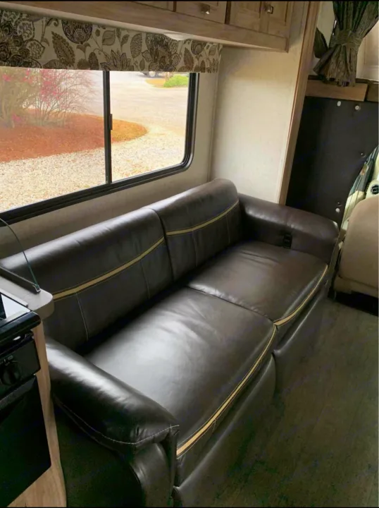 Spacious RV rental interior featuring a large leather-like sofa, window with outdoor view, and ample storage for trips.. Forester LE 2018