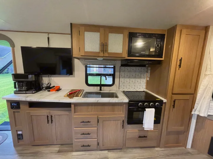 This RV rental's modern kitchen boasts a sink, stove, microwave, and TV, perfect for on-the-go living.. Forest River Prime time Avenger 2023