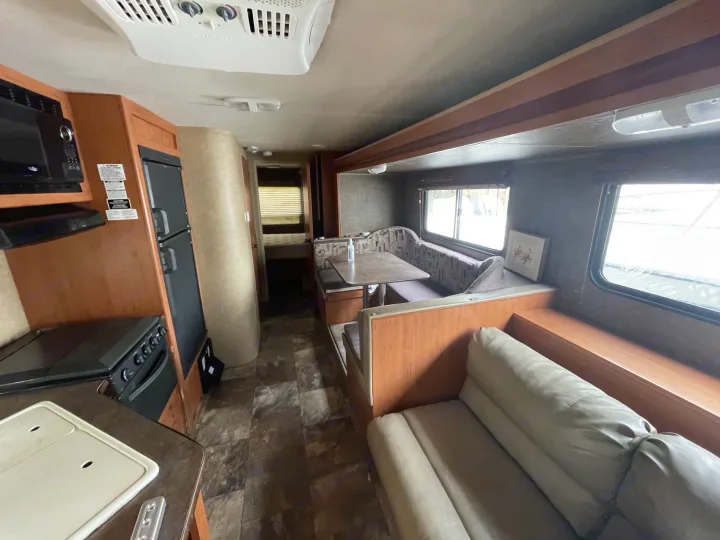 View inside an RV showing the kitchen with appliances, dinette, and seating area. Great for your next rv rental.. Forest River Cherokee Grey Wolf 2015