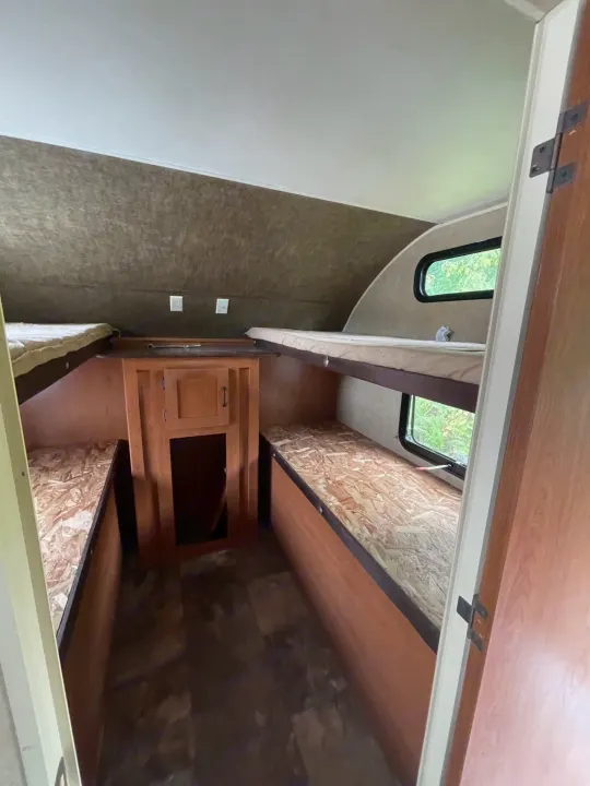 RV rental bunkhouse interior with upper mattresses and lower bare bunks, plus central storage. Perfect for family adventures.. Forest River Cherokee Grey Wolf 2015