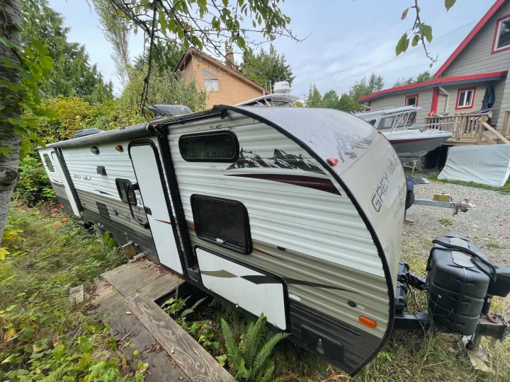 Grey Wolf travel trailer. An RV rental option parked in a leafy yard with homes and boats nearby.. Forest River Cherokee Grey Wolf 2015