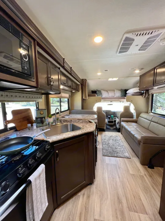 Spacious RV rental interior with full kitchen, dinette, sofa, and cab-over bed, creating a comfortable living space.. Thor Four Winds 2020