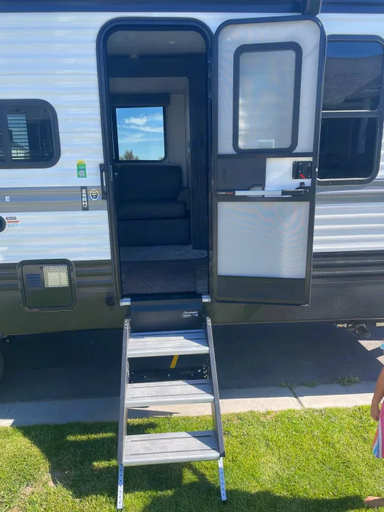 RV rental's open travel trailer door, showing sturdy entry steps, and a glimpse of the modern interior.. Keystone RV Hideout 2022