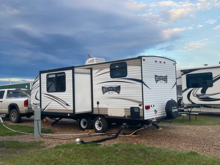 This white Forest River Wildwood RV rental is set up with utilities at a gravel campsite.. Forest River Wildwood X-Lite 2016