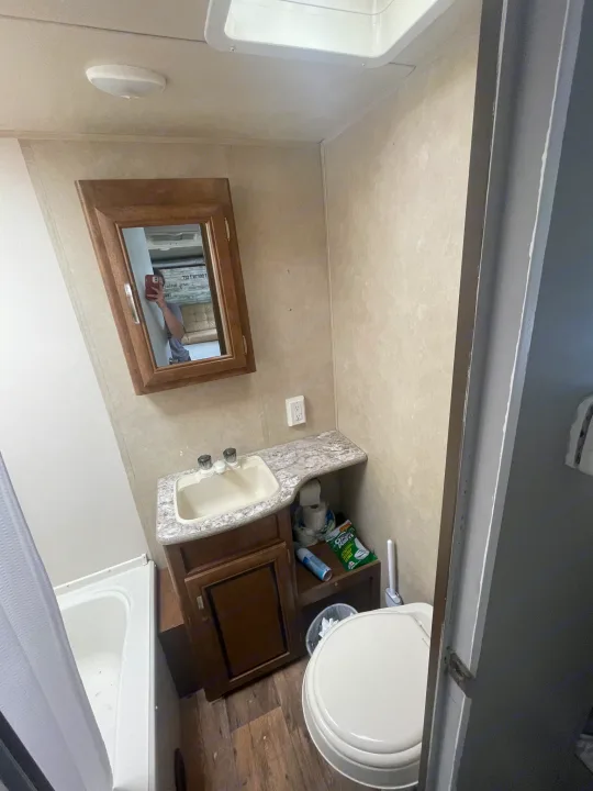 Compact RV rental bathroom interior: sink vanity, mirror, toilet, and small tub/shower combination.. Forest River Wildwood X-Lite 2016