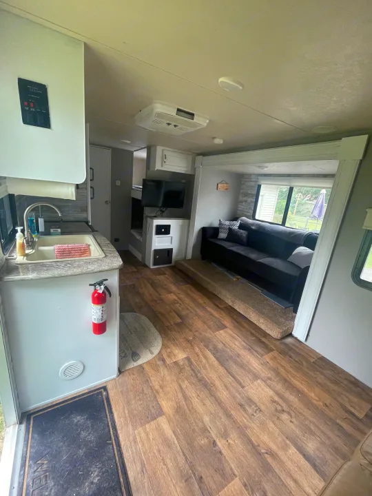 RV rental interior: A bright, modern space with a kitchen sink, dark sofa, and wood-look floors.. Forest River Wildwood X-Lite 2016