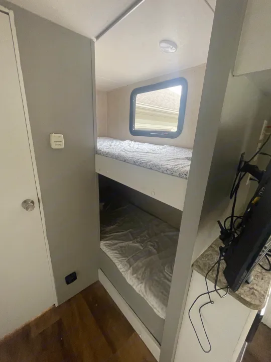 Inside this RV rental: comfortable bunk beds, a window, and a wall-mounted thermostat.. Forest River Wildwood X-Lite 2016
