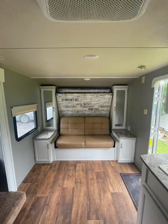 RV rental's inviting interior: convertible couch/bed, wood-look floor, white storage cabinets, and bright windows.. Forest River Wildwood X-Lite 2016