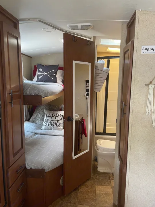 Explore this RV rental's compact interior, featuring cozy bunk beds with themed pillows, and a functional bathroom with a toilet and shower.. Forest River Surveyor 2014