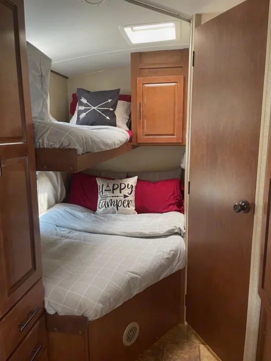 Inside this RV rental: comfortable bunk beds with playful pillows, offering a cozy sleeping space for travelers.. Forest River Surveyor 2014