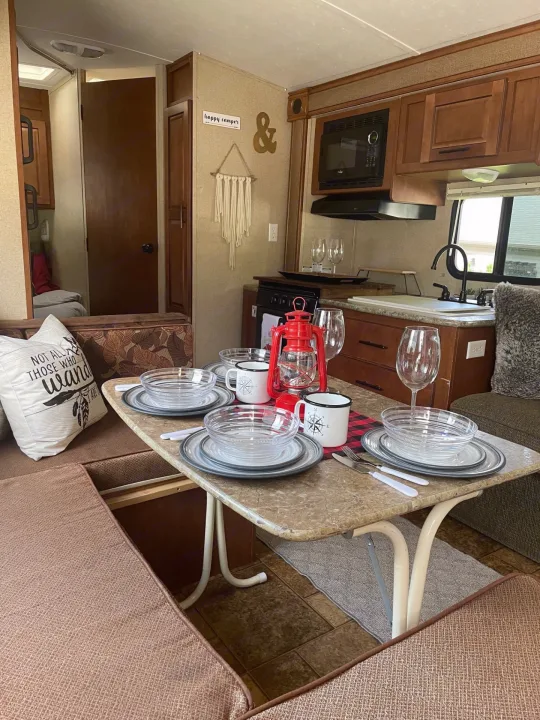 This RV rental interior showcases a cozy dinette with full place settings and an adjacent kitchen.. Forest River Surveyor 2014