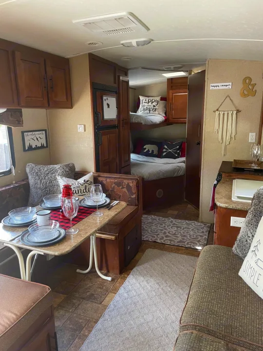 Cozy RV rental interior: a fully set dining area, comfortable bunks, and rustic decor for your next camper adventure.. Forest River Surveyor 2014
