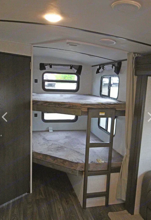 Inside an RV rental: a cozy bunkhouse area with two beds, windows, and a ladder, great for family travel.. Keystone RV Bullet Ultra Lite 2021