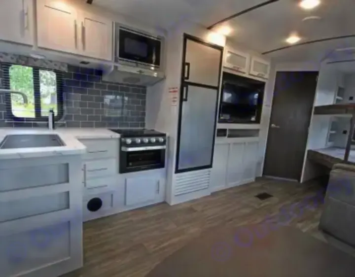 Explore a modern RV rental's bright interior! Features a full kitchen with microwave, stove, sink, fridge, plus TV and bunk beds.. Keystone RV Bullet Ultra Lite 2021