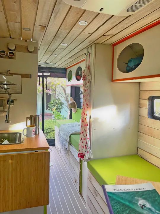RV rental interior: cozy wooden ceiling, bright green cushions, a functional kitchenette, and sunny outdoor view.. Dodge Ram Van Roadtrek 2019