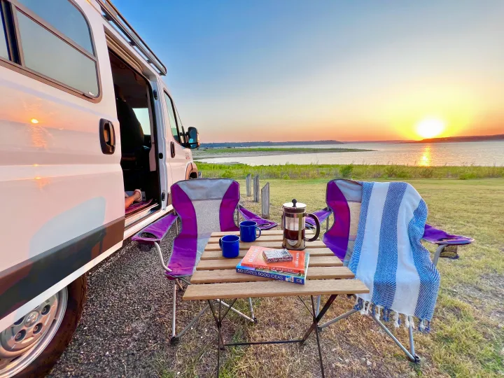 Serene sunset from an RV rental, with coffee, books, and cozy chairs by the lake. A perfect evening escape.. Dodge RAM Promaster 2017