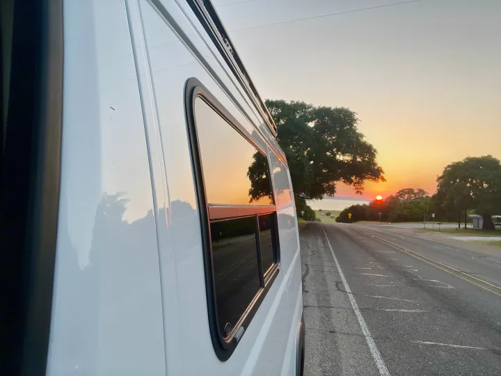 Scenic sunset reflecting on an RV rental parked roadside, a perfect travel adventure vista.. Dodge RAM Promaster 2017