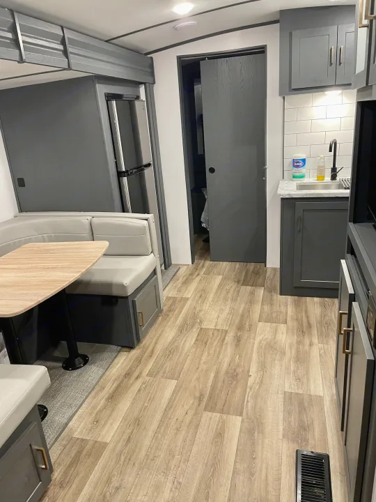 Step inside this modern RV rental featuring a cozy dinette, full kitchen, and light wood flooring for your next adventure.. Keystone RV Bullet Ultra Lite 2022
