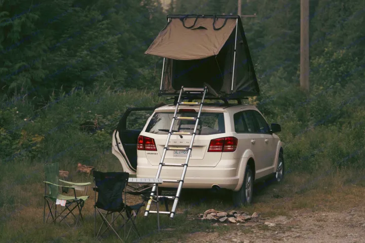 A white SUV with a deployed rooftop tent and ladder, set up for camping. An ideal RV rental for your next outdoor adventure.. Dodge Journey 2013