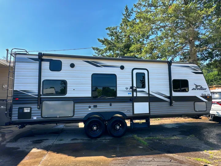 Modern travel trailer RV, a Jay Flight Baja, sits on a sunny day. Your next RV rental adventure awaits!. Jayco Jay Flight SLX 2022