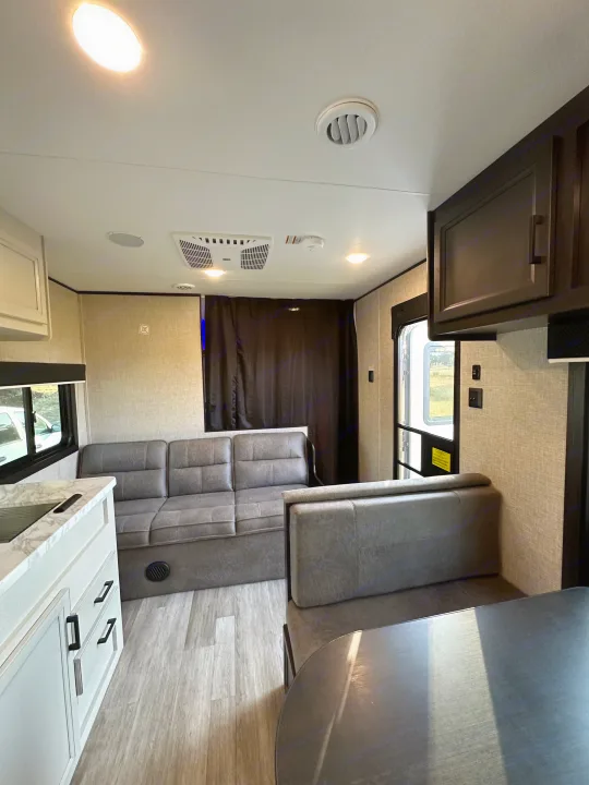 Step inside this RV rental's modern interior: light kitchen cabinets, grey sofa, dinette, and wood-look flooring.. Jayco Jay Flight SLX 2022