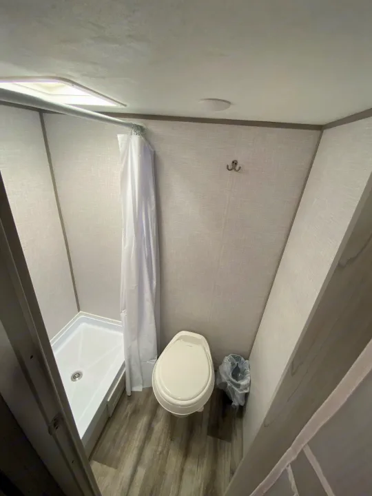 RV rental: View of a compact bathroom with a standing shower, toilet, and small trash bin, designed for efficient space use.. Dutchmen Coleman Lantern LT 2023