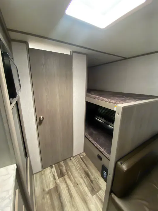 Spacious RV rental interior with bunk beds, microwave, and wood flooring. Perfect for your next adventure!. Dutchmen Coleman Lantern LT 2023
