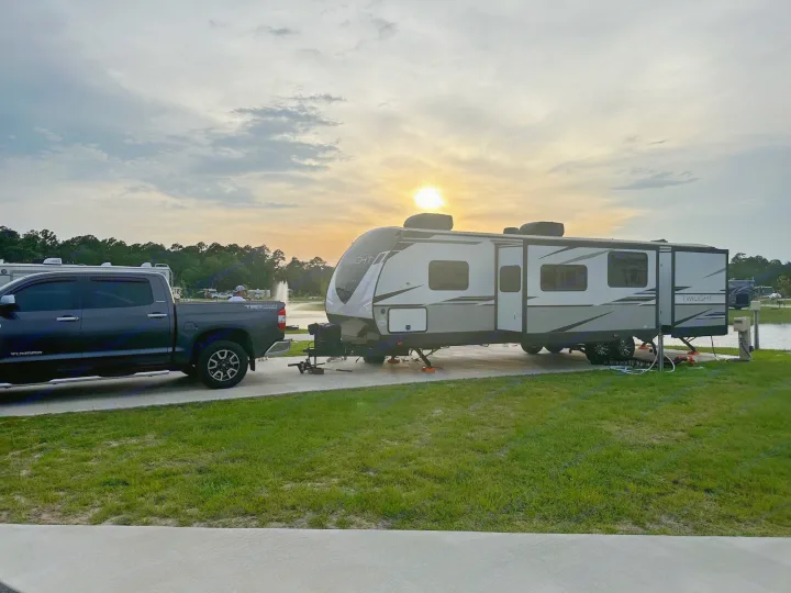 RV rental at sunset: A truck and travel trailer parked at a lakeside campsite, perfect for outdoor adventures.. Twilight RVS Signature 2022