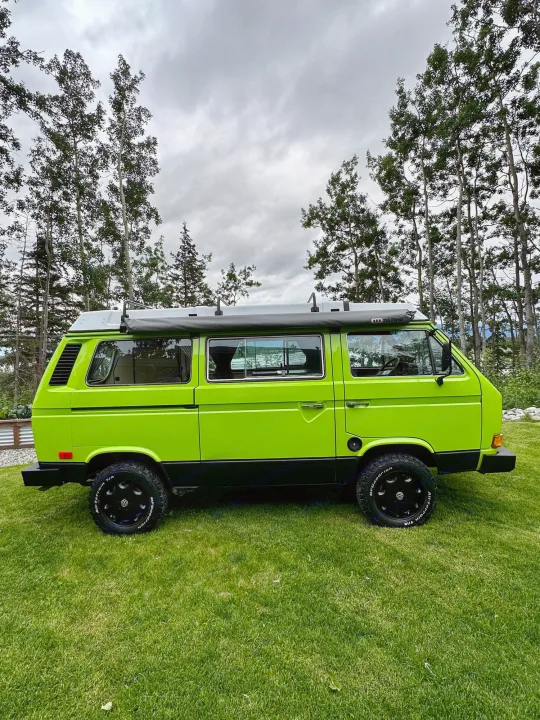 A vibrant lime green VW Vanagon camper van is parked on green grass. Ideal for an RV rental & outdoor adventures!. Volkswagen Westfalia 1984