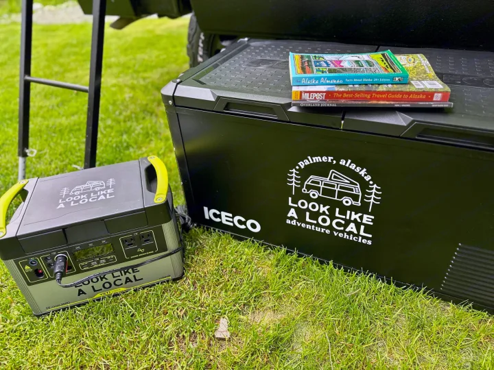 Preparing for an Alaska RV rental adventure with an Iceco cooler, Goal Zero power station, and travel guides on grass.. Volkswagen Westfalia 1984