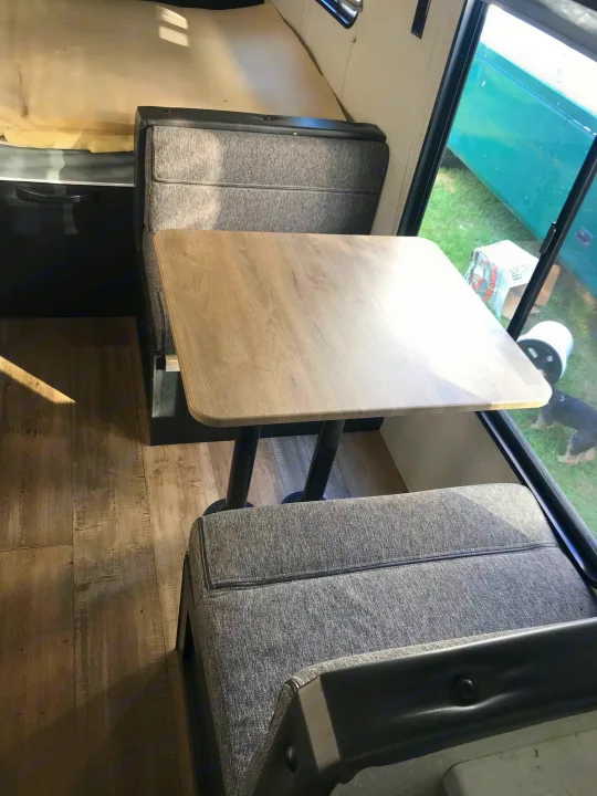 Experience a comfortable RV rental: dinette area with a light wood table and cozy grey seating, looking out.. Forest River Cherokee Wolf Pup 2022
