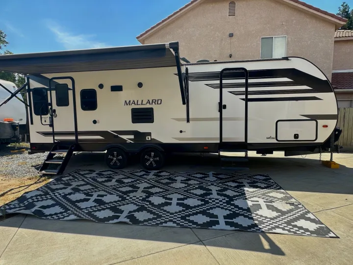 An RV rental travel trailer with extended awning & outdoor mat, parked for leisure. Great for camping.. Heartland Other 2021