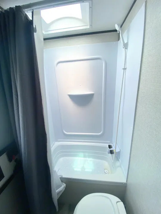 RV rental: Bright, compact bathroom with a shower-tub combo, handheld shower, skylight, and toilet.. Aspen Trail Aspen Trail Trailer 2021