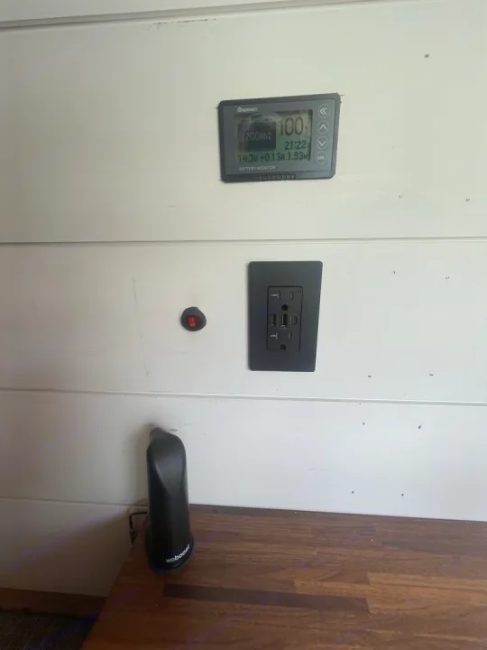RV rental power essentials: Renogy battery monitor, AC/USB outlets, and WeBoost cell booster on wood and white paneling.. Mercedes Sprinter 2010