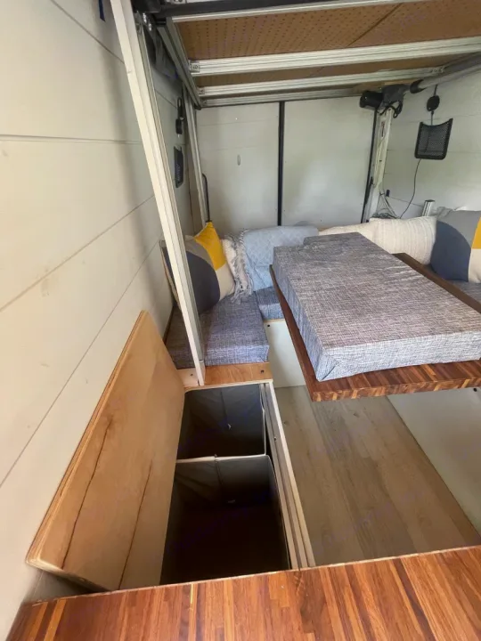 Inside an RV rental: a versatile camper van interior with a bed/seating area, storage access, and cozy decor.. Mercedes Sprinter 2010