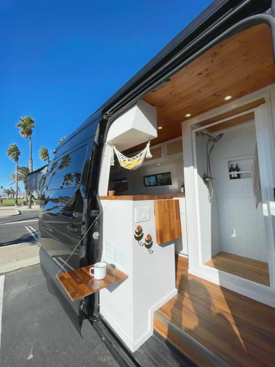 Luxurious RV rental: Custom camper van interior with wood ceiling, full tile shower, and exterior table for your next adventure.. Mercedes-Benz Sprinter 2021