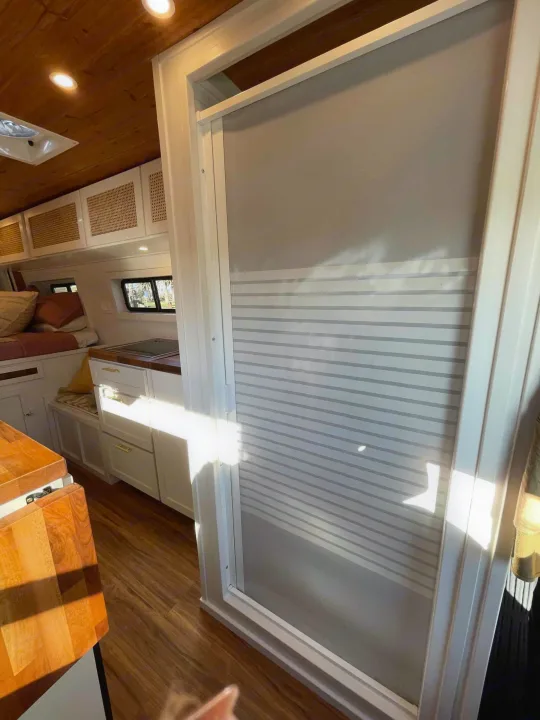 RV rental interior with a cozy bedroom, compact kitchenette, and smart storage, featuring a stylish striped divider.. Mercedes-Benz Sprinter 2021